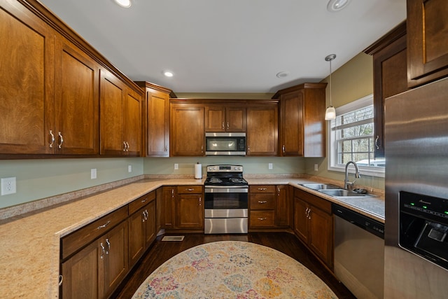 kitchen featuring sink, dark wood-type flooring, appliances with stainless steel finishes, and pendant lighting