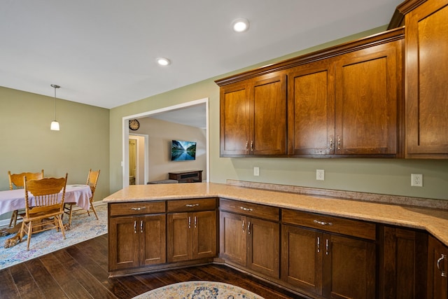 kitchen with kitchen peninsula, dark hardwood / wood-style flooring, and decorative light fixtures