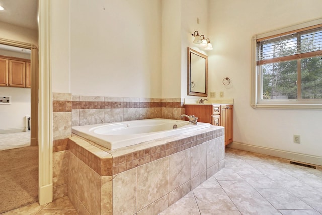 bathroom featuring tile patterned floors, vanity, and a relaxing tiled tub