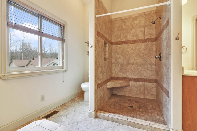 bathroom featuring tile patterned floors, toilet, and tiled shower