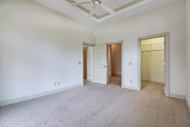 unfurnished bedroom with a closet, ceiling fan, a spacious closet, and light colored carpet