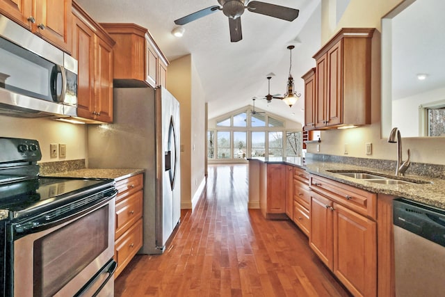 kitchen with lofted ceiling, hanging light fixtures, stainless steel appliances, sink, and light stone counters