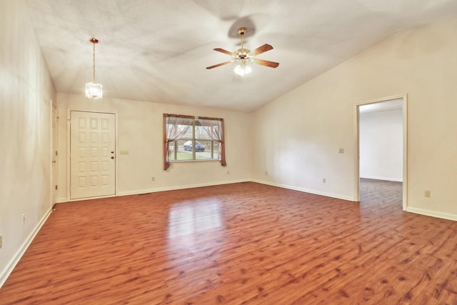 spare room with lofted ceiling, dark wood-type flooring, ceiling fan with notable chandelier, and baseboards