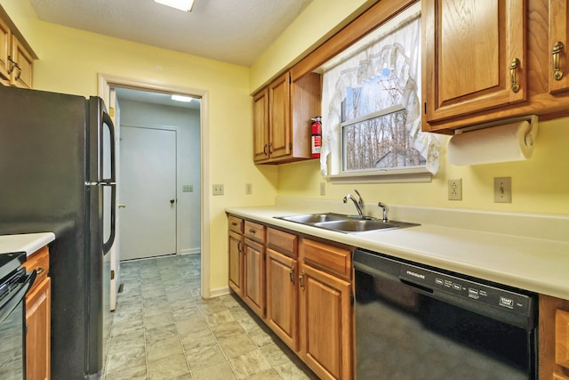 kitchen featuring brown cabinets, black appliances, light countertops, and a sink