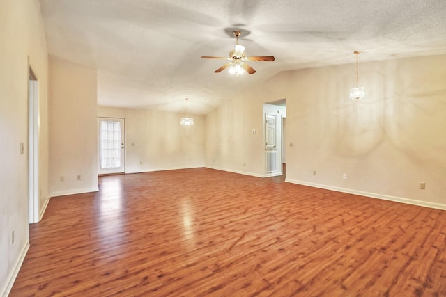 unfurnished room with baseboards, wood finished floors, vaulted ceiling, a textured ceiling, and ceiling fan with notable chandelier