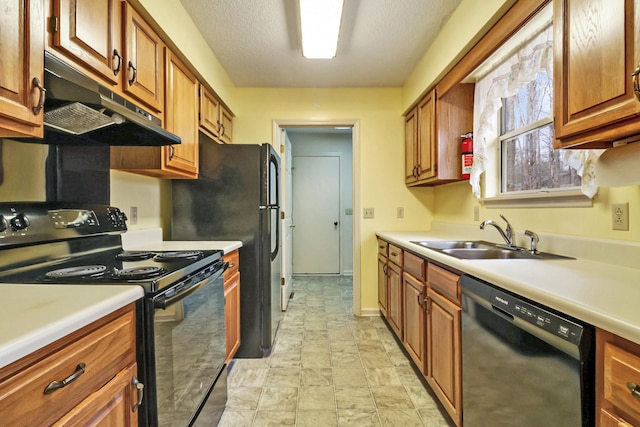 kitchen featuring under cabinet range hood, a sink, light countertops, black appliances, and brown cabinetry