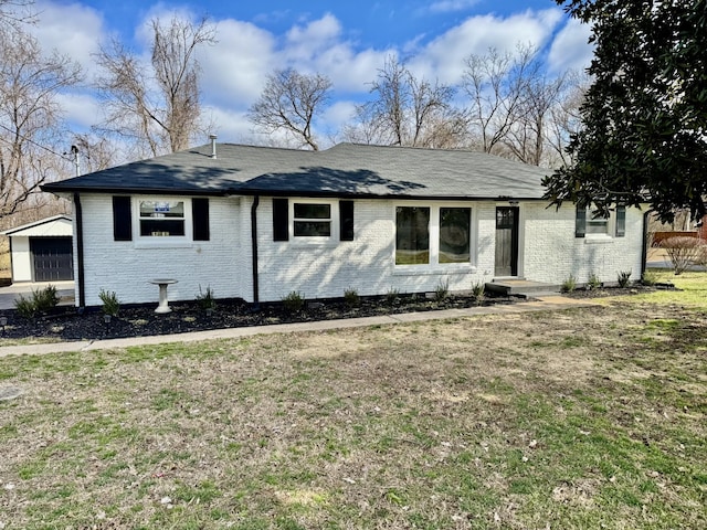 ranch-style house featuring an outbuilding, brick siding, a front yard, and a shingled roof