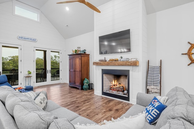 living room with wood-type flooring, french doors, a large fireplace, ceiling fan, and high vaulted ceiling