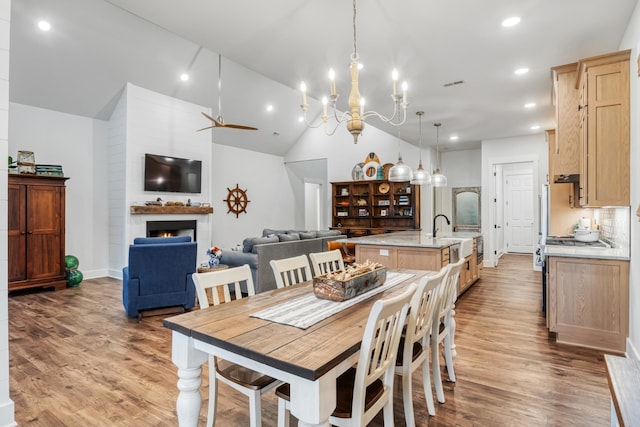 dining area featuring a fireplace, vaulted ceiling, sink, and wood-type flooring