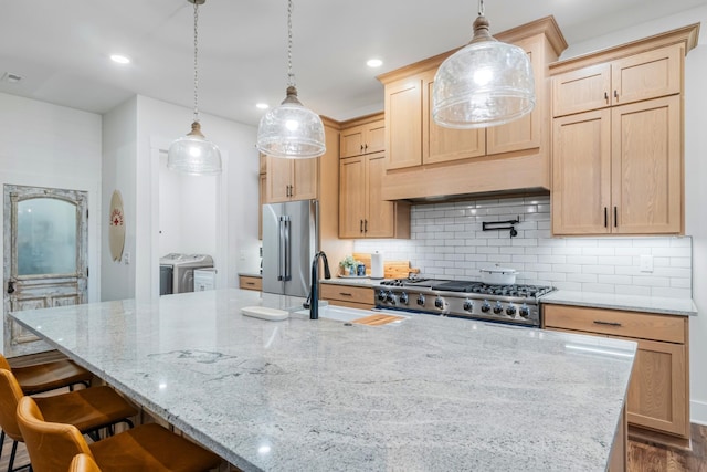 kitchen featuring hanging light fixtures, high end refrigerator, separate washer and dryer, and light brown cabinets