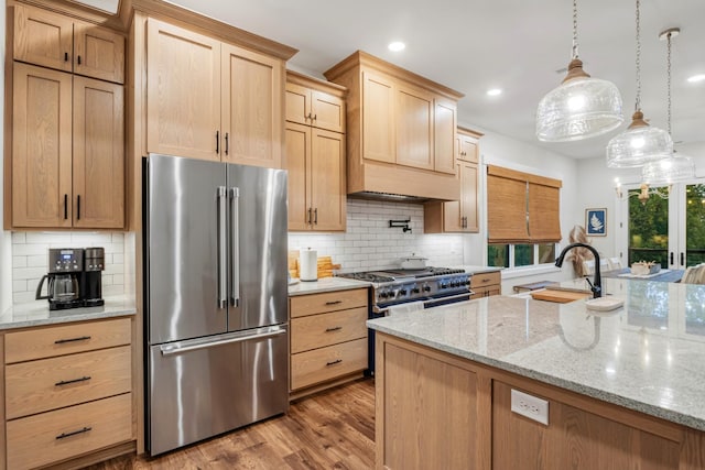 kitchen featuring light hardwood / wood-style floors, backsplash, light stone counters, high quality appliances, and pendant lighting