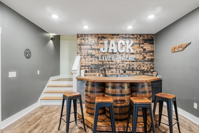 bar featuring light wood-type flooring and butcher block counters