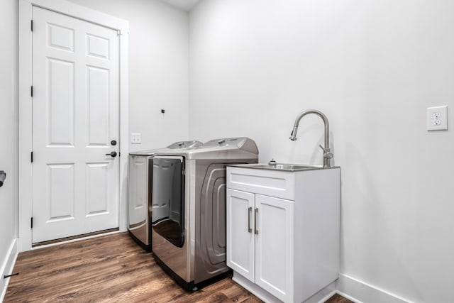 clothes washing area featuring sink, cabinets, dark hardwood / wood-style flooring, and washing machine and clothes dryer