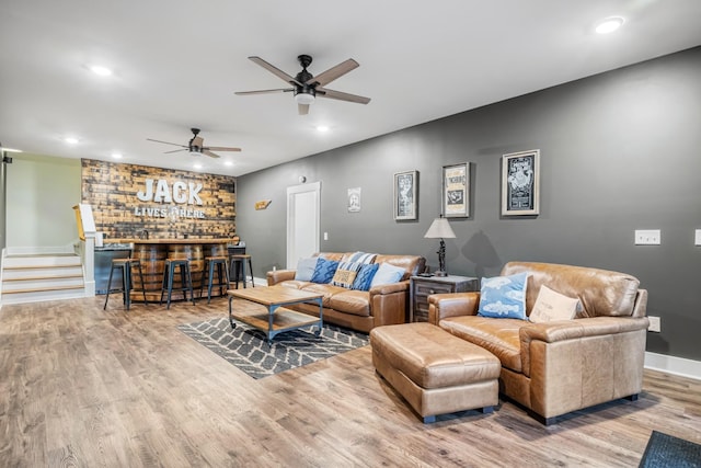 living room featuring ceiling fan, wood-type flooring, and bar area