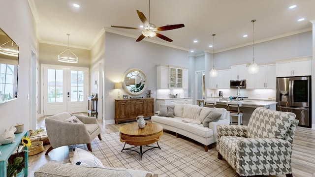 living room with ornamental molding, french doors, a towering ceiling, and light hardwood / wood-style flooring