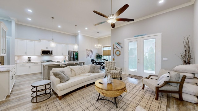 living room featuring light wood-type flooring, crown molding, and french doors