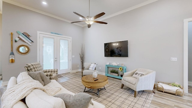 living room with light wood-type flooring, french doors, ornamental molding, and ceiling fan