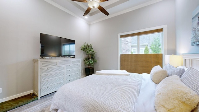 bedroom featuring light wood-type flooring, crown molding, a tray ceiling, and ceiling fan