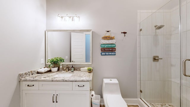 bathroom with vanity, a shower with door, and toilet