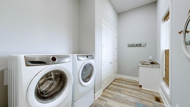 laundry room featuring washer and clothes dryer and light hardwood / wood-style flooring