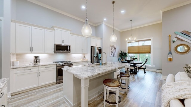 kitchen with a center island with sink, appliances with stainless steel finishes, and white cabinets