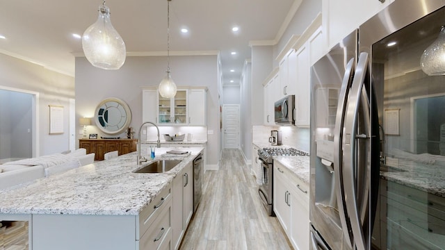 kitchen with hanging light fixtures, white cabinetry, stainless steel appliances, and sink