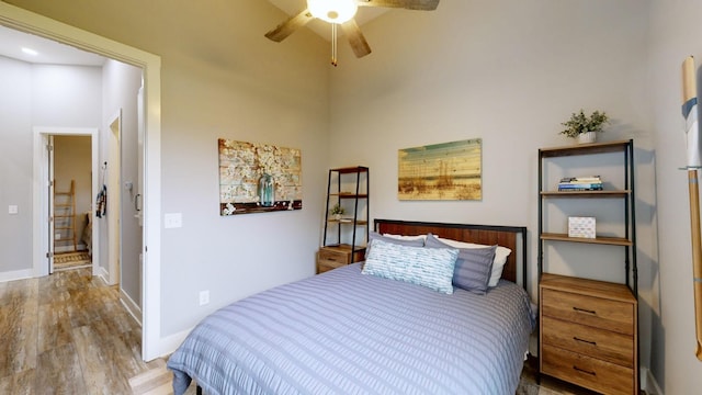 bedroom with light wood-type flooring, ceiling fan, and a high ceiling