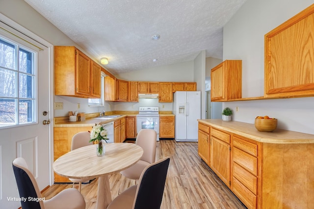 kitchen with light countertops, vaulted ceiling, light wood-type flooring, white appliances, and under cabinet range hood