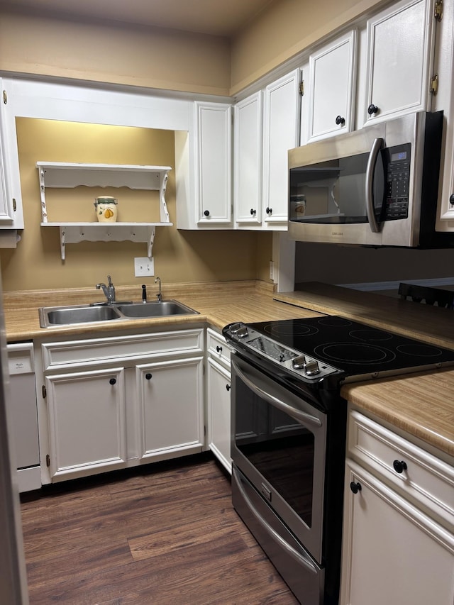 kitchen with appliances with stainless steel finishes, white cabinetry, dark hardwood / wood-style floors, and sink