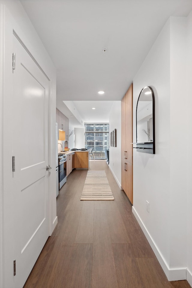 hallway featuring dark wood-style floors, recessed lighting, and baseboards