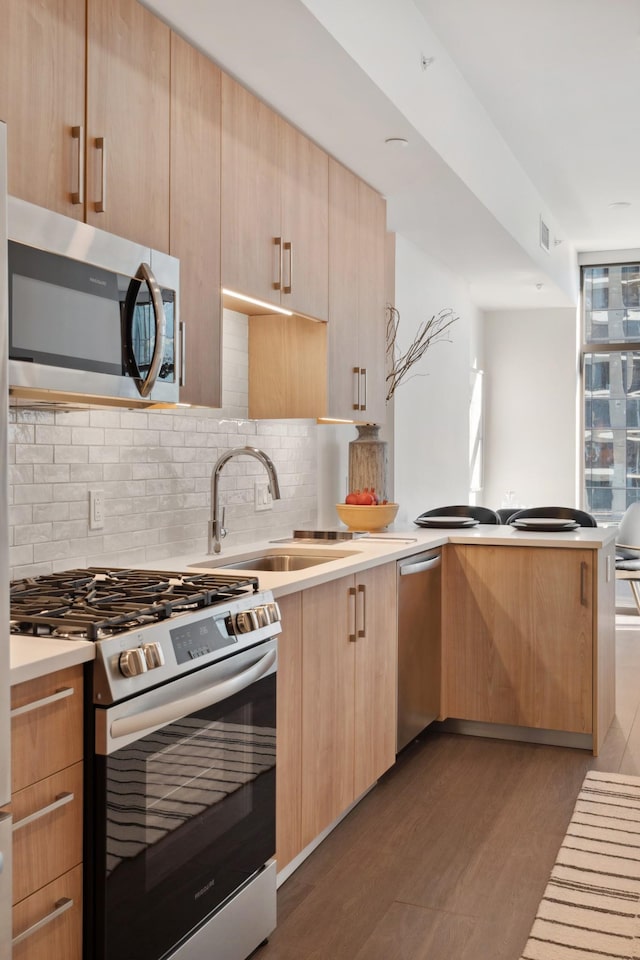 kitchen with sink, tasteful backsplash, dark wood-type flooring, appliances with stainless steel finishes, and light brown cabinetry