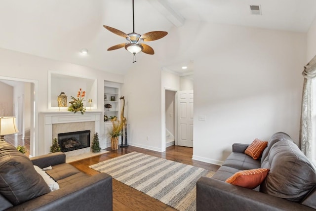 living room with dark wood-type flooring, a high end fireplace, lofted ceiling with beams, and built in features