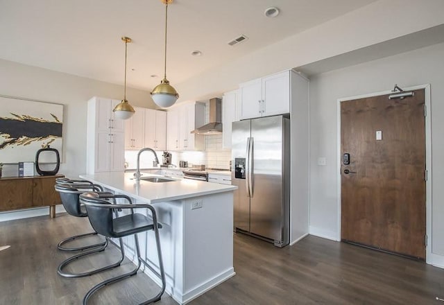 kitchen with sink, wall chimney range hood, white cabinetry, and stainless steel appliances