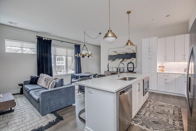 kitchen featuring appliances with stainless steel finishes, wood-type flooring, pendant lighting, sink, and white cabinetry