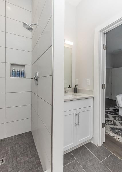 bathroom with vanity, tiled shower, and tile patterned floors