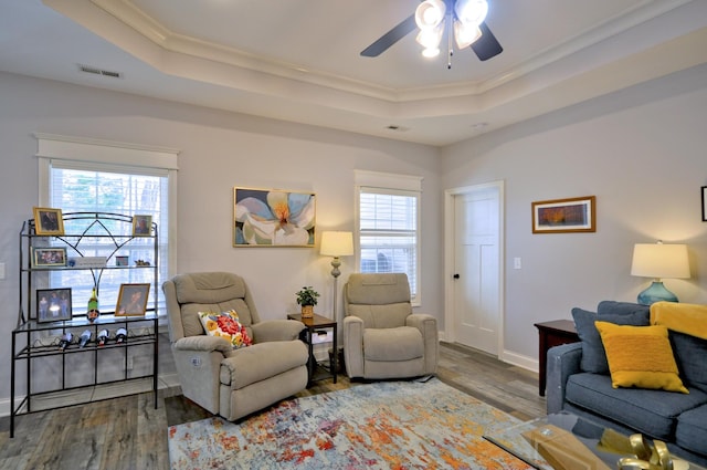 living room with hardwood / wood-style floors, a healthy amount of sunlight, and a raised ceiling