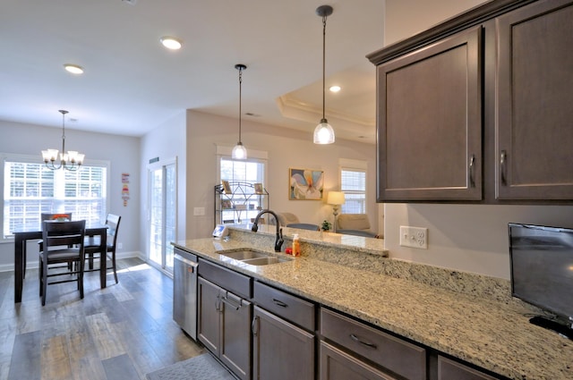 kitchen featuring hanging light fixtures, sink, dark brown cabinets, light stone counters, and dishwasher
