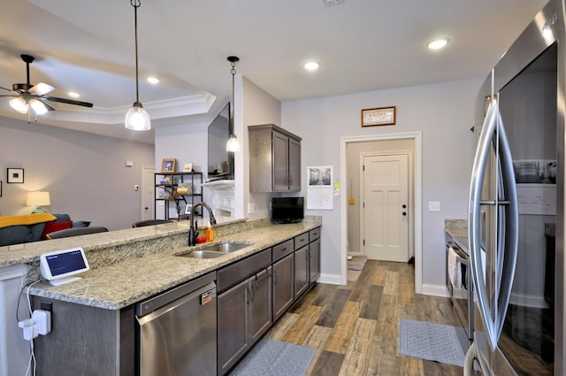kitchen with sink, light stone counters, stainless steel appliances, hanging light fixtures, and dark brown cabinetry
