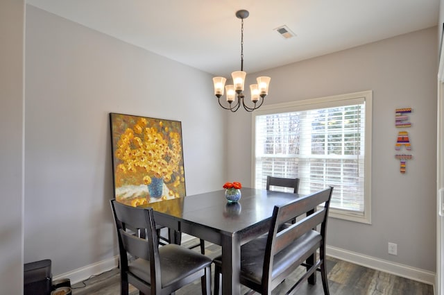 dining space featuring dark wood-type flooring and a chandelier