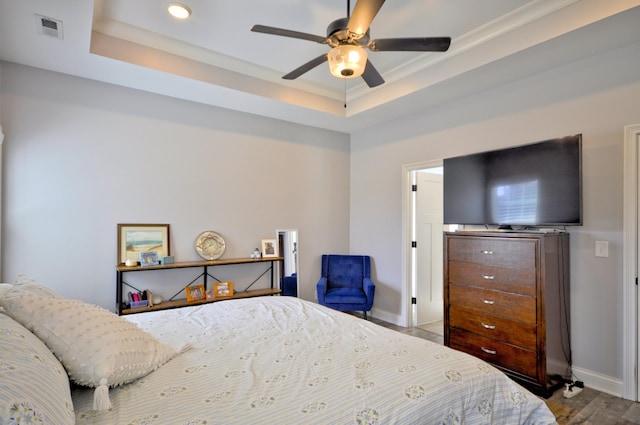 bedroom with a tray ceiling, ceiling fan, and wood-type flooring