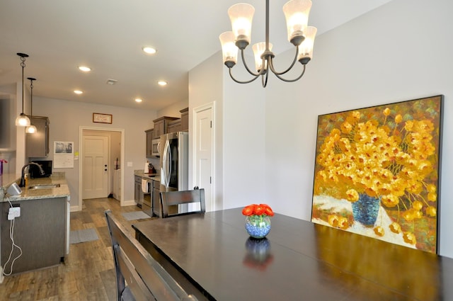 dining area with hardwood / wood-style flooring, sink, and a notable chandelier