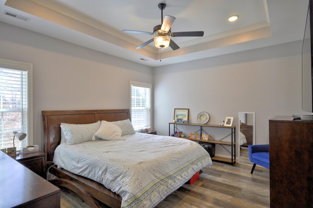 bedroom featuring hardwood / wood-style flooring, ceiling fan, and a raised ceiling