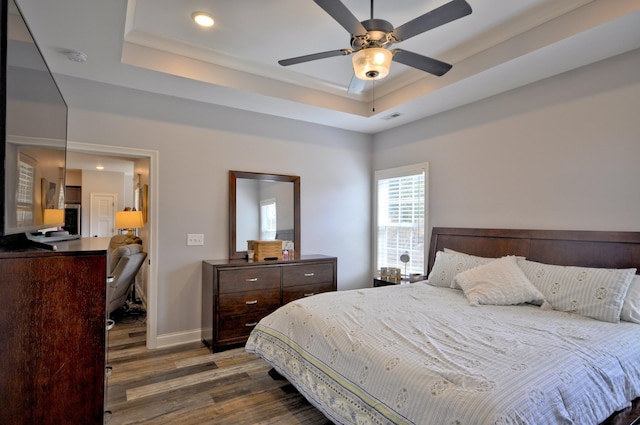 bedroom featuring ceiling fan, a tray ceiling, and dark hardwood / wood-style floors