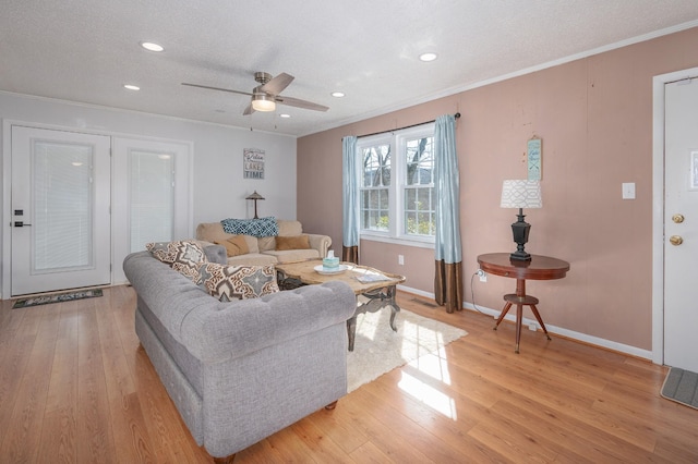 living area with ornamental molding, a ceiling fan, light wood finished floors, and a textured ceiling