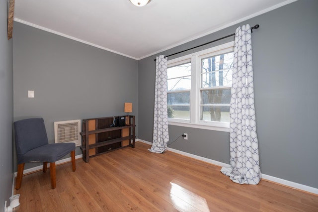 sitting room with crown molding, heating unit, baseboards, and wood finished floors