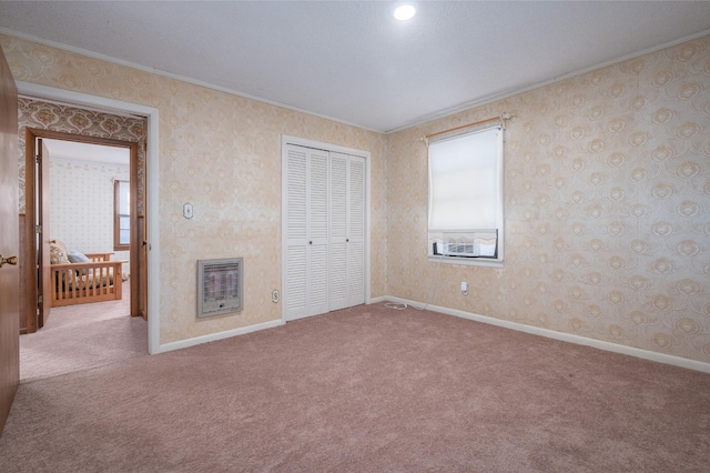 unfurnished bedroom with a closet, ornamental molding, heating unit, a high end fireplace, and carpet flooring