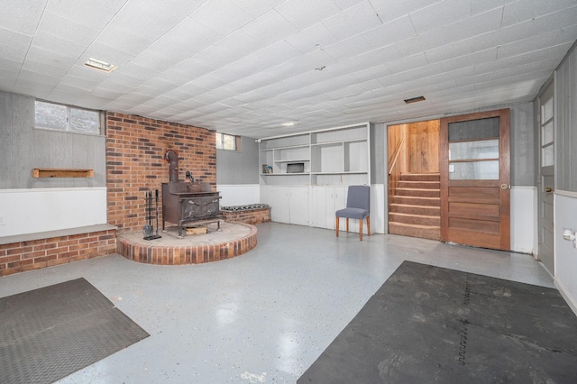 living area with stairway, visible vents, plenty of natural light, and a wood stove