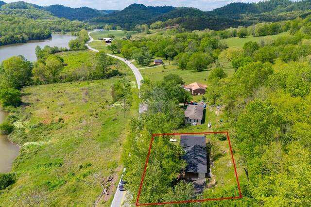 birds eye view of property featuring a water and mountain view and a wooded view