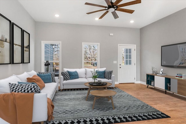 living room featuring baseboards, a ceiling fan, light wood-style flooring, and recessed lighting