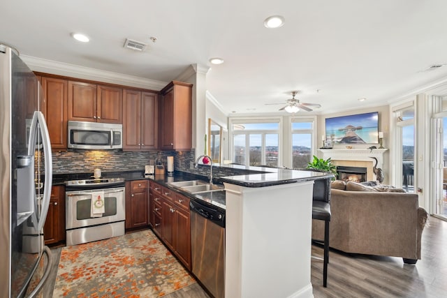 kitchen featuring a breakfast bar area, stainless steel appliances, backsplash, sink, and kitchen peninsula